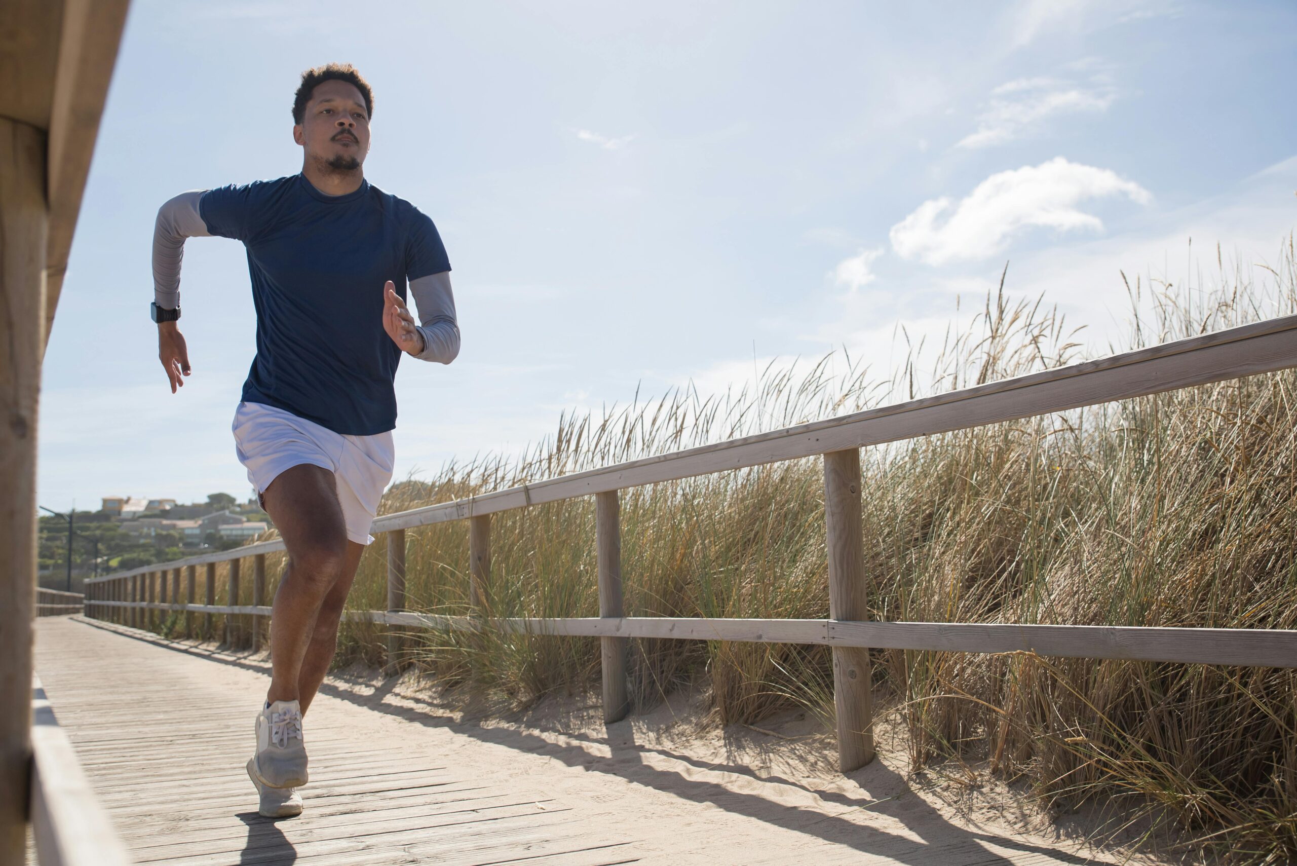 Man running on a trail amidst a grassy field.